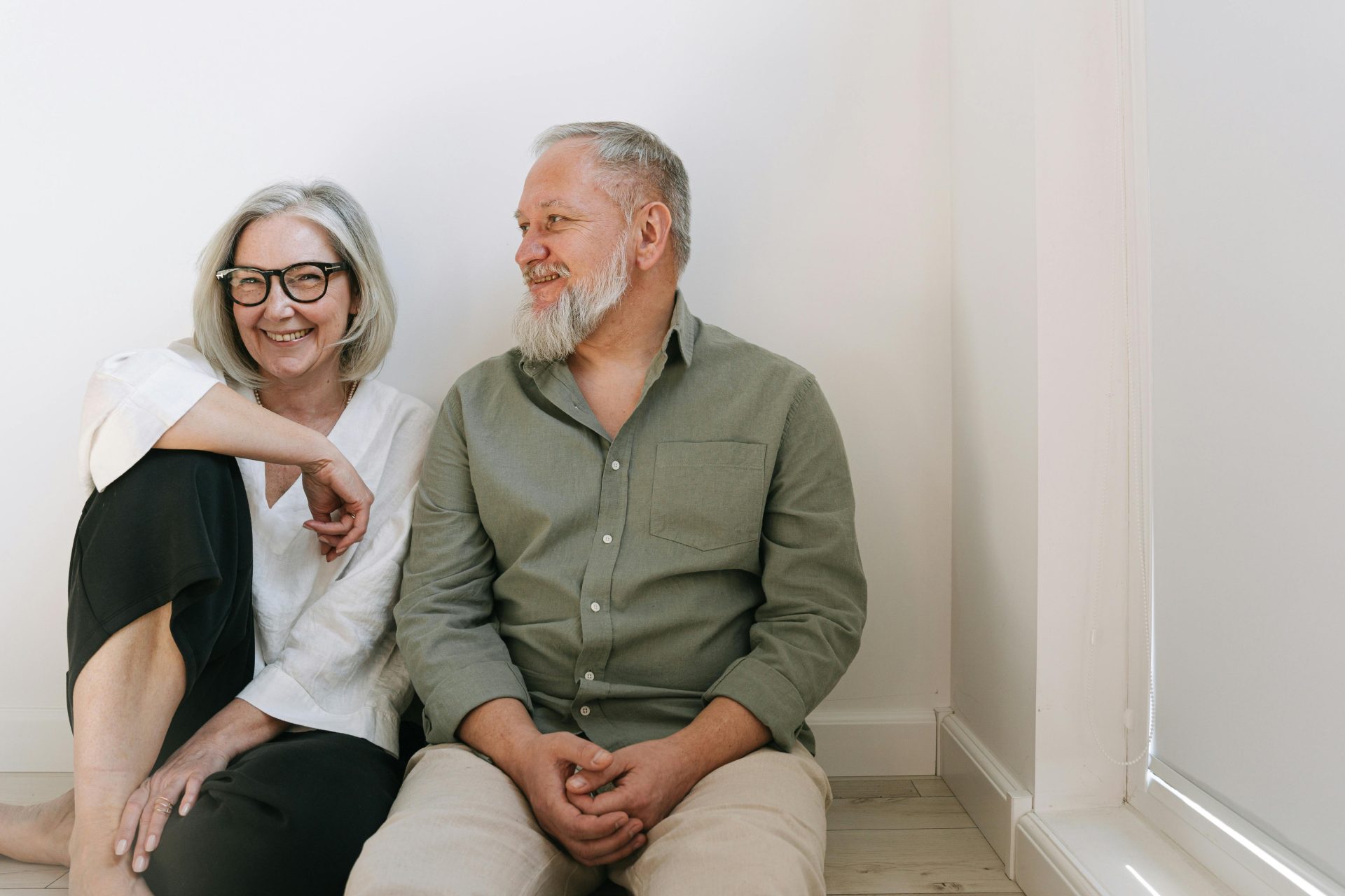 Joyful senior couple sitting together indoors, sharing smiles and love.
