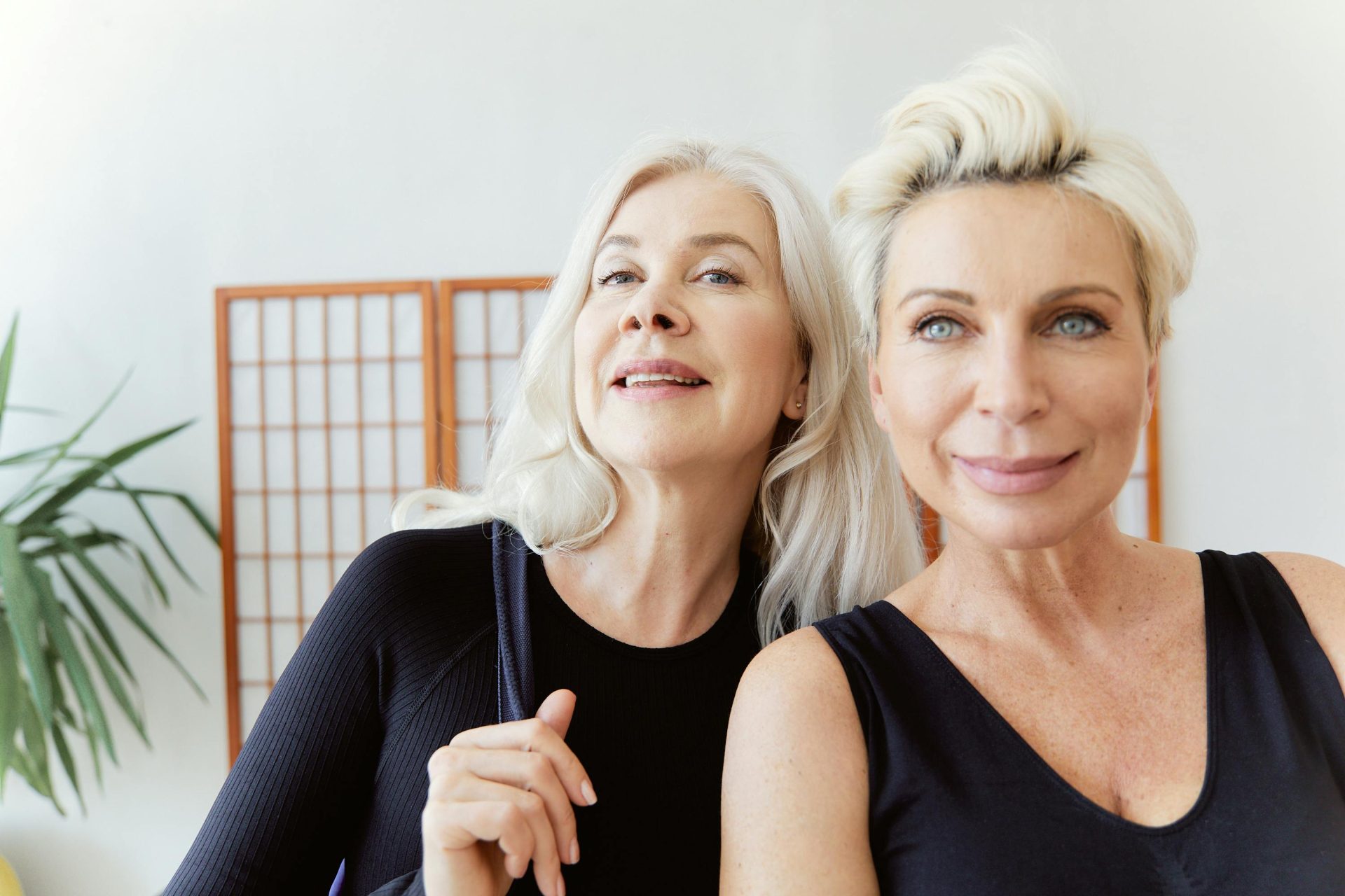 Two senior women smiling indoors, enjoying friendship and bonding. Bright, cheerful mood.